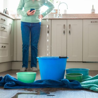 Worried home owner dealing with water leak in the kitchen