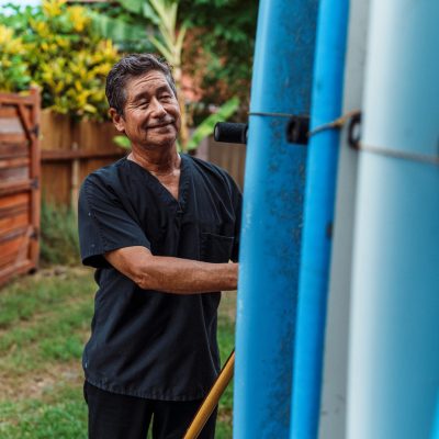 Active senior man loading surfboard onto car before going to work